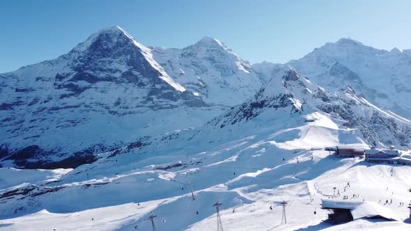 a beautiful ski area in the foreground, eiger, mönch and jungfrau in the background, lots of snow an alt