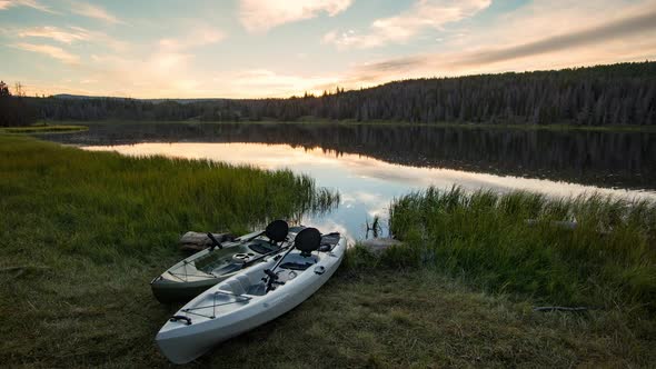 Time lapse of two kayaks lying by lake at sunset alt