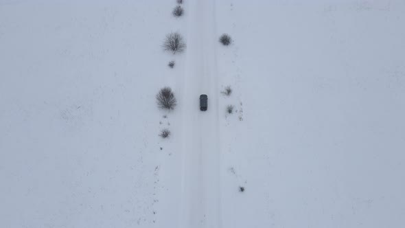 Aerial Drone Top View of Car Vehicle Driving on Snowy Road Landscapes in Winter
