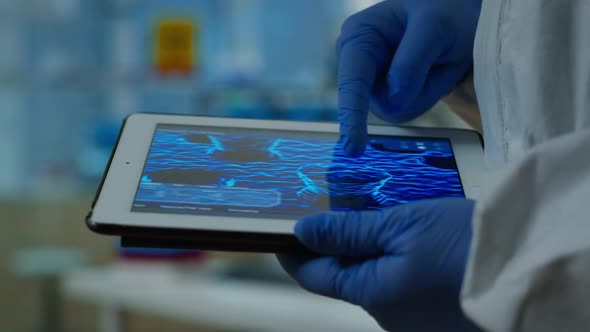 Close Up of Chemist Doctor Working on Tablet with DNA Scan Image alt