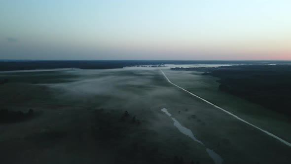 Foggy dawn in the countryside. Foggy river valley and rising sun. Aerial photography.
