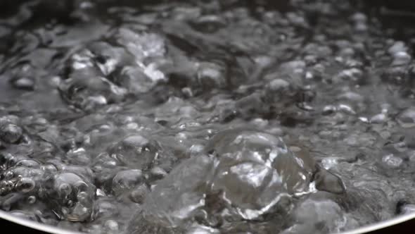 Slow Motion Shot of Boiling Water. Bubbles of Boiling Water Background. Cooking Concept alt