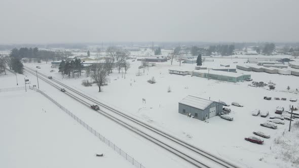 Aerial view of countryside and highway during a winter storm. Mountains and forest in the background