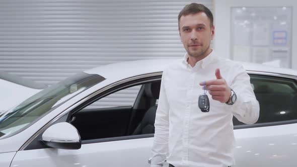 Attractive Young Man Smiling Happily Holding Car Keys To His Newly Bought Car alt