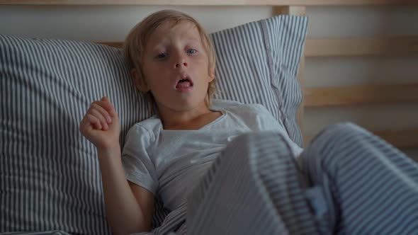 Sick Little Boy in a Bed. Superslowmotion Shot of a Boy Coughing in Bed alt