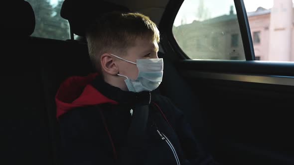 Portrait Child Boy in Protective Face Mask Looks Out Moving Car Window on Street