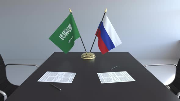 Flags of Saudi Arabia and Russia and Papers on the Table alt