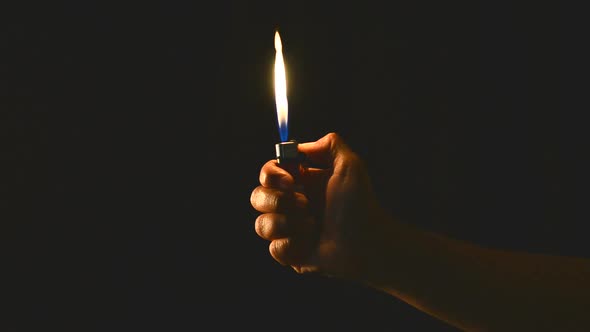 hand hold a burning lighter in the dark