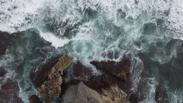 Top down aerial view of giant ocean waves crashing and foaming in coral beach alt