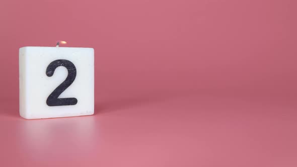 A square candle saying the number 2 being lit and blown out alt