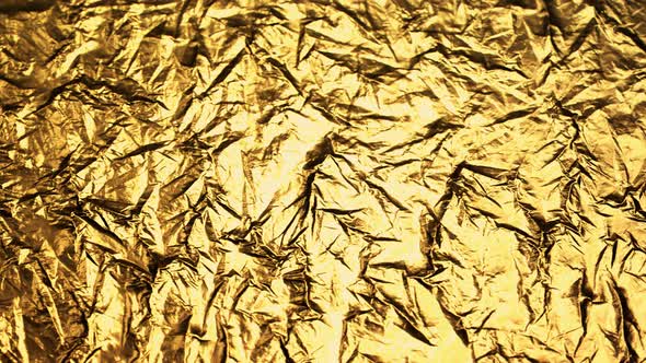 Crumpled, golden foil shining in the spotlight. Endless, abstract pattern. 4K HD