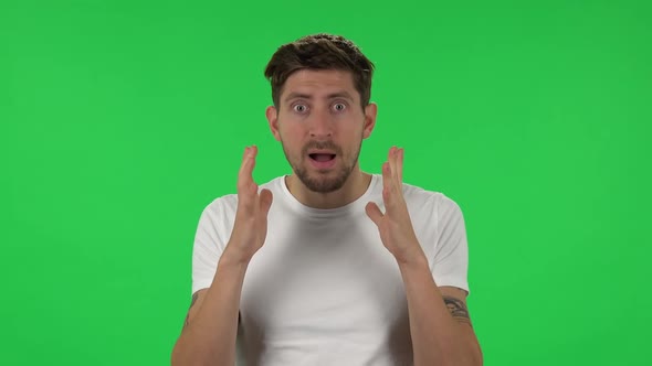 Portrait of Confident Guy Is Looking at Camera with Anticipation, Then Very Upset. Green Screen alt