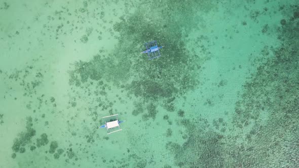 Slowly rotating aerial bird's eye view of banca boats sitting in Badian Bay off the coast of Moalboa alt