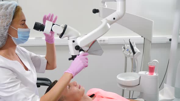 Female Dentist Treating Male Patient Using White Proffessional Microscope