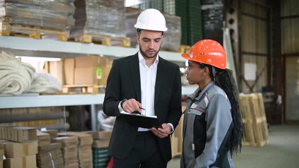 A young manager and a warehouse worker discuss the availability of goods alt