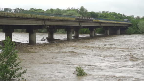 Bridge Over the Overflowing River. Stormy Water Flows. Extremely High Water Level in the River