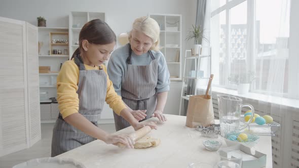 Girl Rolling Out Cookie Dough while Cooking with Grandma alt