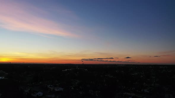 A drone shot over a suburban neighborhood during a golden sunrise. The camera dolly in to the horizo alt