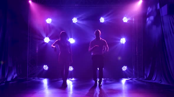 Young Couple Dancing Latin Music. Bachata, Merengue, Salsa. Shot in a Dark Studio with Neon Lights alt