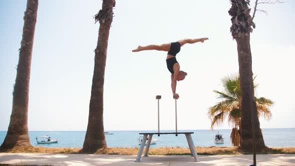 Gymnastics By the Sea  a Young Blonde Woman Training on the High Small Beams  Doing a Handstand alt
