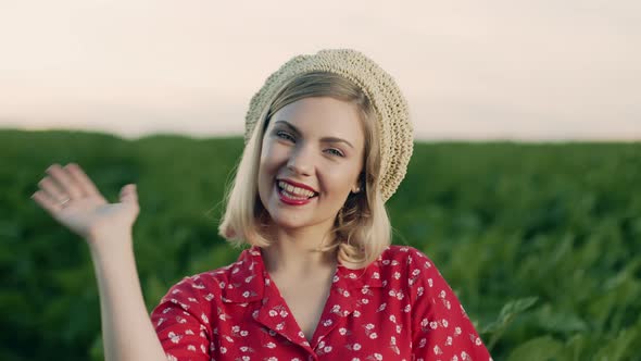 Beautiful Portrait of Attractive Blonde Woman Waving Hand, Smiling, Greeting. Lady in Straw Beret alt