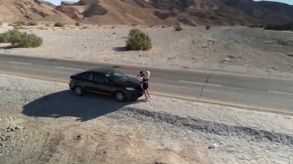 Aerial Shot of Couple Hugging and Kissing While Standing Near the Car While Traveling Outdoors