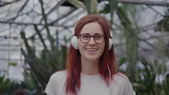 Woman in Headphones Listens To Music, Looks at the Camera, Smiles alt