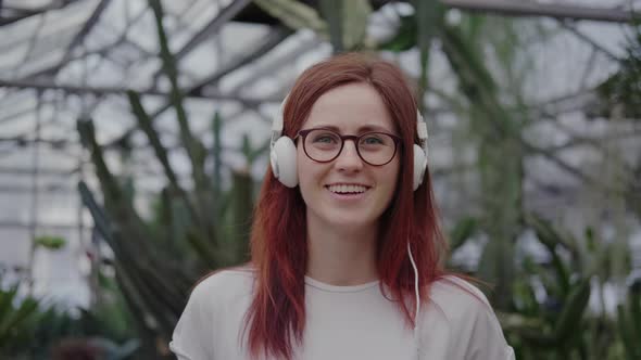 Woman in Headphones Listens To Music, Looks at the Camera, Smiles