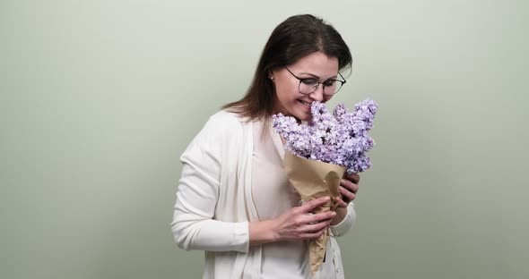 Happy Smiling Mature Woman with Bouquet of Flowers on Green Pastel Background