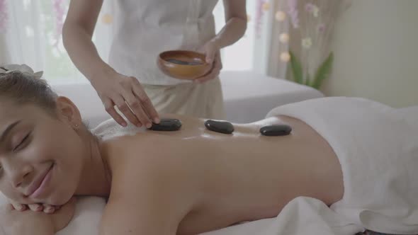 Young woman having hot stone massage in spa, relax and aromatherapy alt