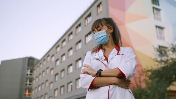 Tired Female Medical Worker in Surgical Face Mask Looks Away alt