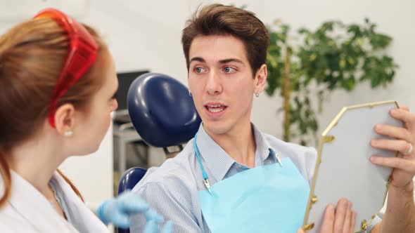Young Man Talking with Female Dentist Before Teeth Whitening Procedure alt