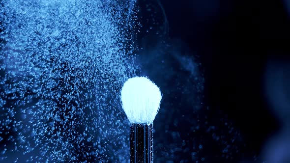 Blue Neon Glowing Ultraviolet Powder on a Makeup Brush Flying Away with Beautiful Vintage Bokeh