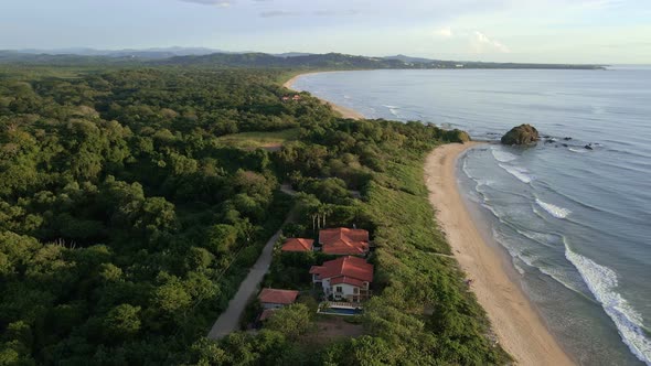 Drone orbiting around beach front resort at Playa Ventanas near Tamarindo, Costa Rica. 90 degree cir alt