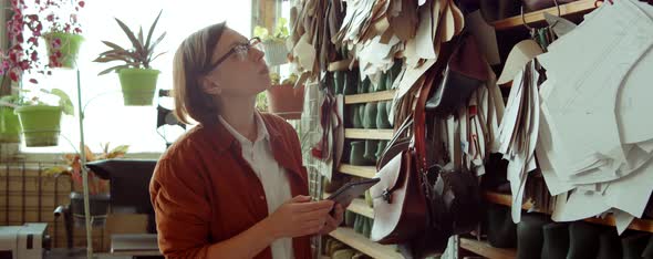Female Shoemaker Working on Tablet in Workshop alt