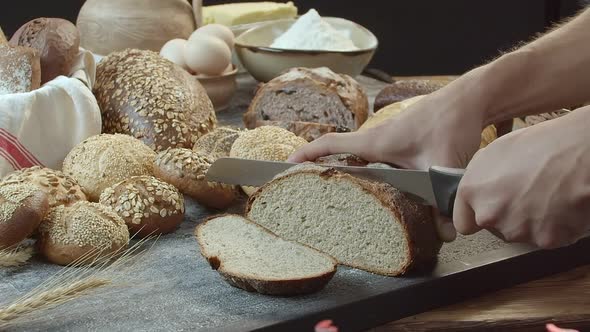 Hands Cutting the Baked Dutch Bread on the Table alt