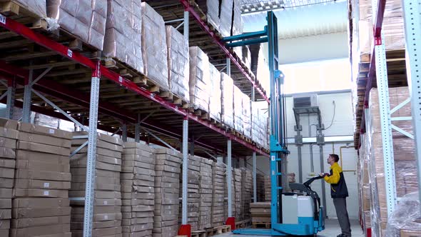 Warehouse Worker Driver in Uniform Loading Cardboard Boxes By Forklift Stacker Loader alt