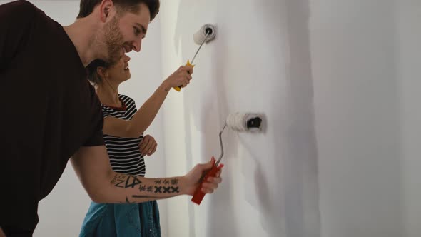 Tracking video of caucasian couple painting wall in new house. Shot with RED helium camera in 8K alt