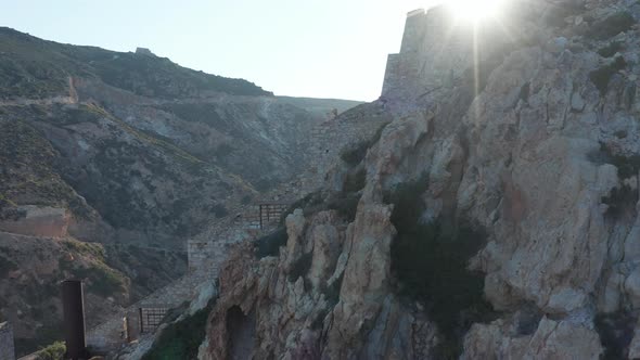 Aerial Close Up View of an Old Mine, Factory Built on the Side of a Mountain in Sunset Light alt
