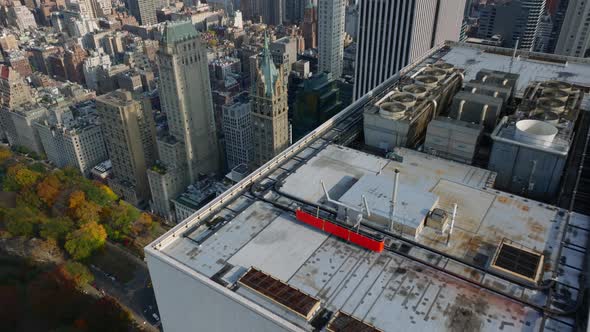 Backwards Fly Above Top of Skyscraper with Rotating Fans of Air Condition Equipment alt