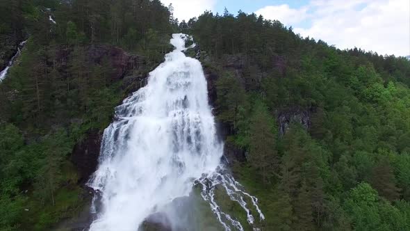 Massive waterfall in norwegian forest, aerial footage alt