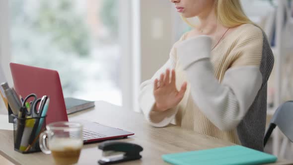 Unrecognizable Slim Blond Woman Gesturing Using Sign Language Sitting at Table with Laptop alt