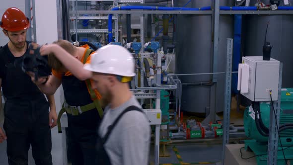 Men at Work in Hard Hats at a Plant with Hazardous Substances Wear a Breathing Mask to Work in a alt