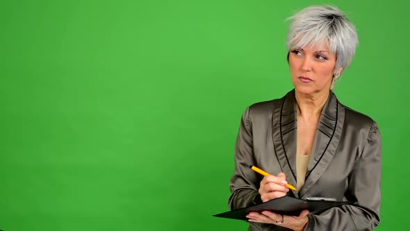 Business Middle Aged Woman Writes To Paper (Serious Face) - Green Screen - Studio alt
