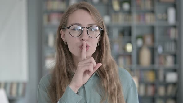 Portrait of Young Woman Gesturing To Be Quiet with Finger on Lips alt