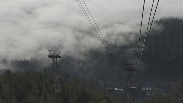 Aerial View of Gondola Tower Over Evergreen Trees Covered During Winter Season Day alt
