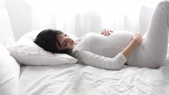 Pregnant Beautiful Woman Lying On Bed And Caressing Baby Belly alt