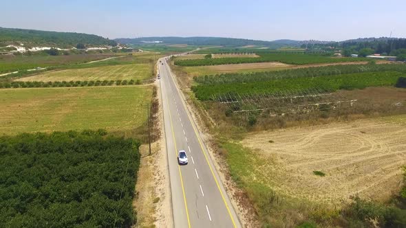 White car driving in a colony near power poles. alt