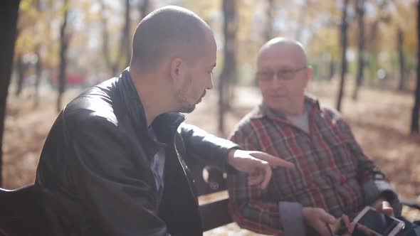 Old Father with Adult Son in Park on a Bench Talk and Drink Coffee alt