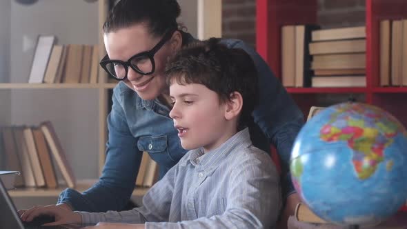 caring teacher helps a student do their homework on a laptop. alt